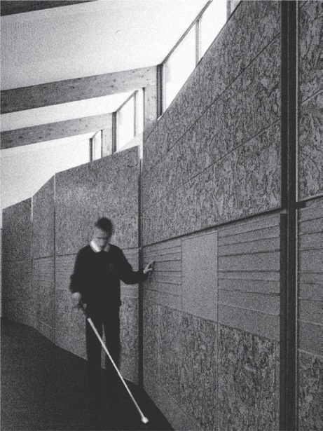 A student with a white cane tracing the textured sensory wall at Glasgow’s Hazelwood School